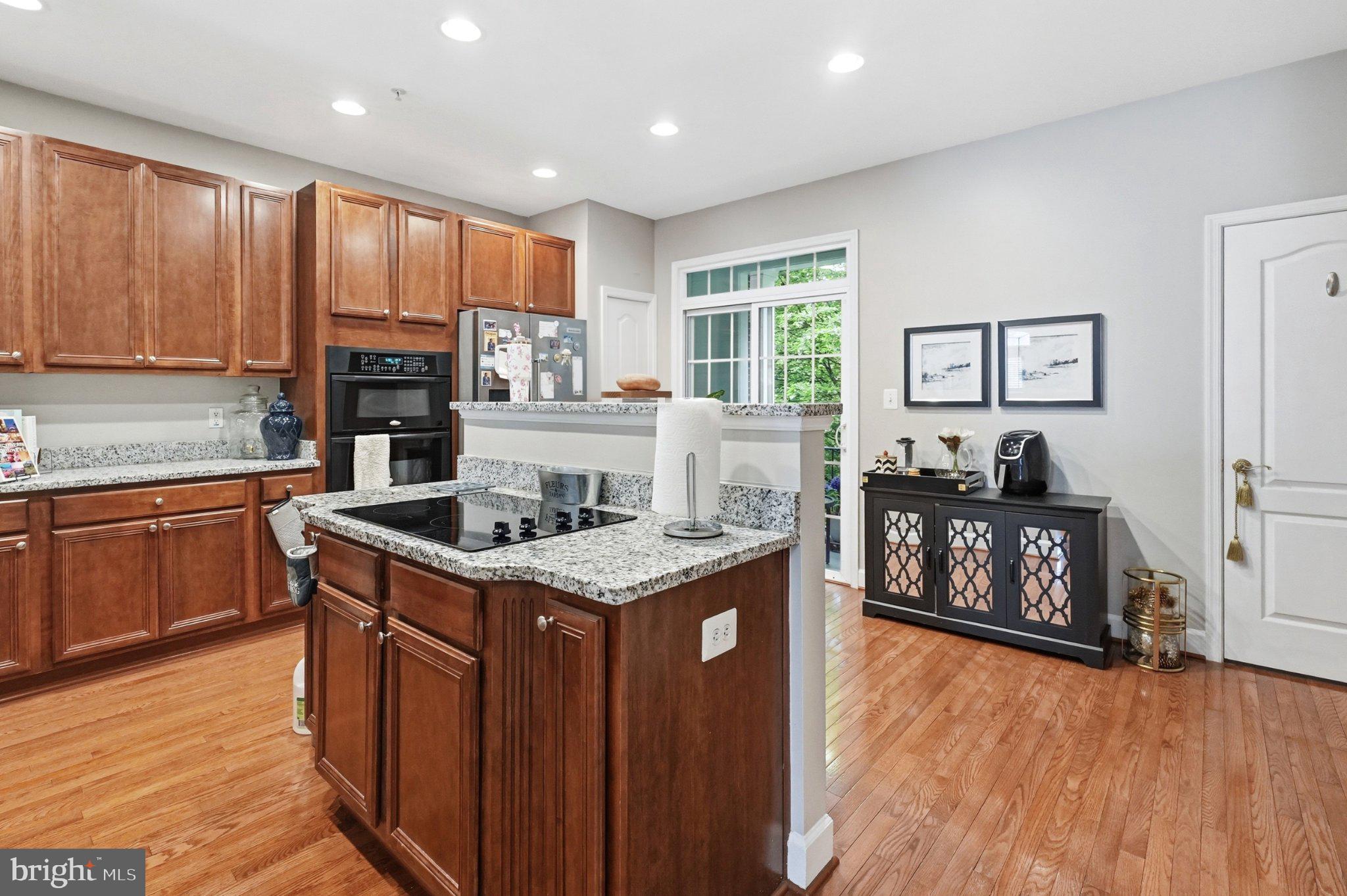 772 Raven Avenue Gaithersburg, MD 20877 - Photo 15 of 30 a kitchen with granite countertop a stove top oven a sink dishwasher and a microwave oven with wooden floor