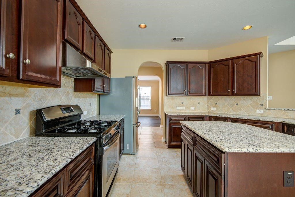 4411 Enchanted Spring Court Sugar Land, TX 77479 - Photo 8 of 21 a kitchen with granite countertop a stove top oven a sink dishwasher and cabinets with wooden floor