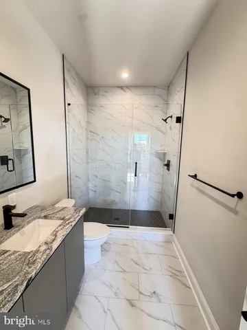 a bathroom with a granite countertop sink mirror vanity and toilet