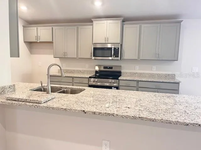 a kitchen with granite countertop a sink and a stove top oven