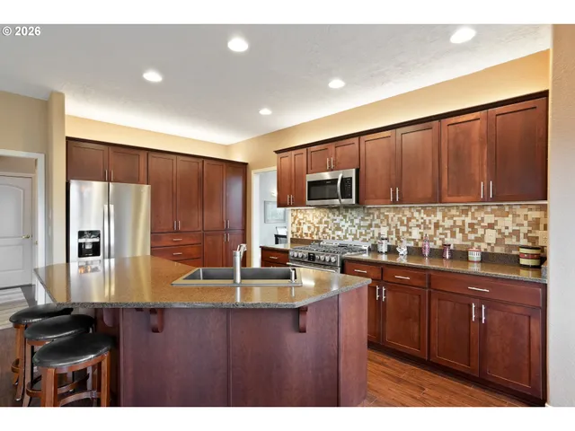 a kitchen with kitchen island granite countertop stainless steel appliances a stove sink and microwave
