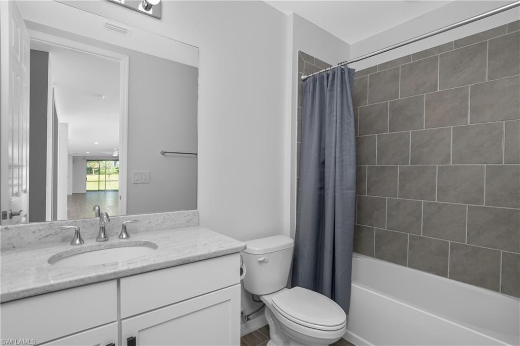 14559 Edgewater Circle Naples, FL 34114 - Photo 18 of 49 a bathroom with a granite countertop sink a toilet and shower