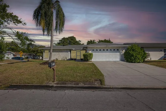 a front view of a house with a yard and car parked