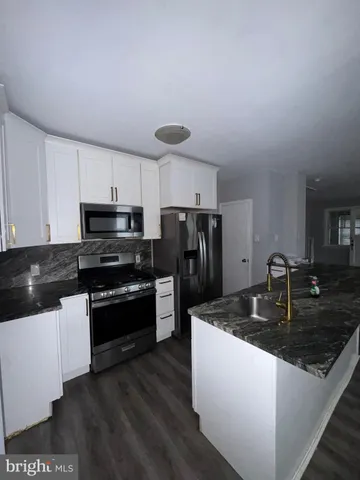 a kitchen with granite countertop a sink a stove top oven and refrigerator