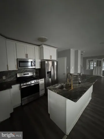 a kitchen with kitchen island granite countertop a sink stove and refrigerator