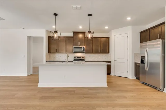 a view of kitchen with stainless steel appliances granite countertop cabinets and a wooden floor