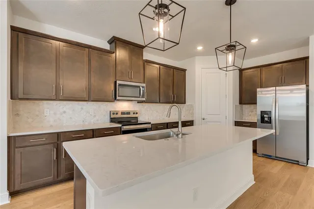 a kitchen with stainless steel appliances granite countertop a sink a stove and a refrigerator
