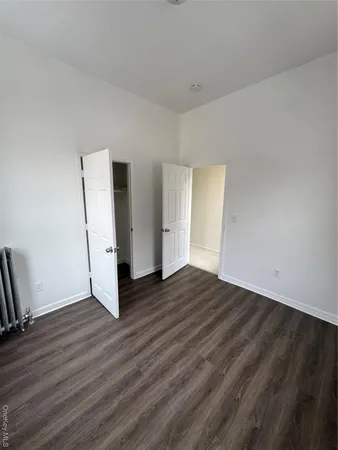 a view of an empty room with wooden floor and a fireplace