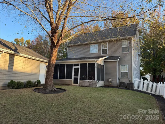 a view of a house with a small yard and a large tree