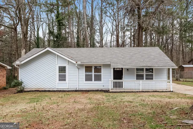 a backyard of a house with large trees and barbeque oven