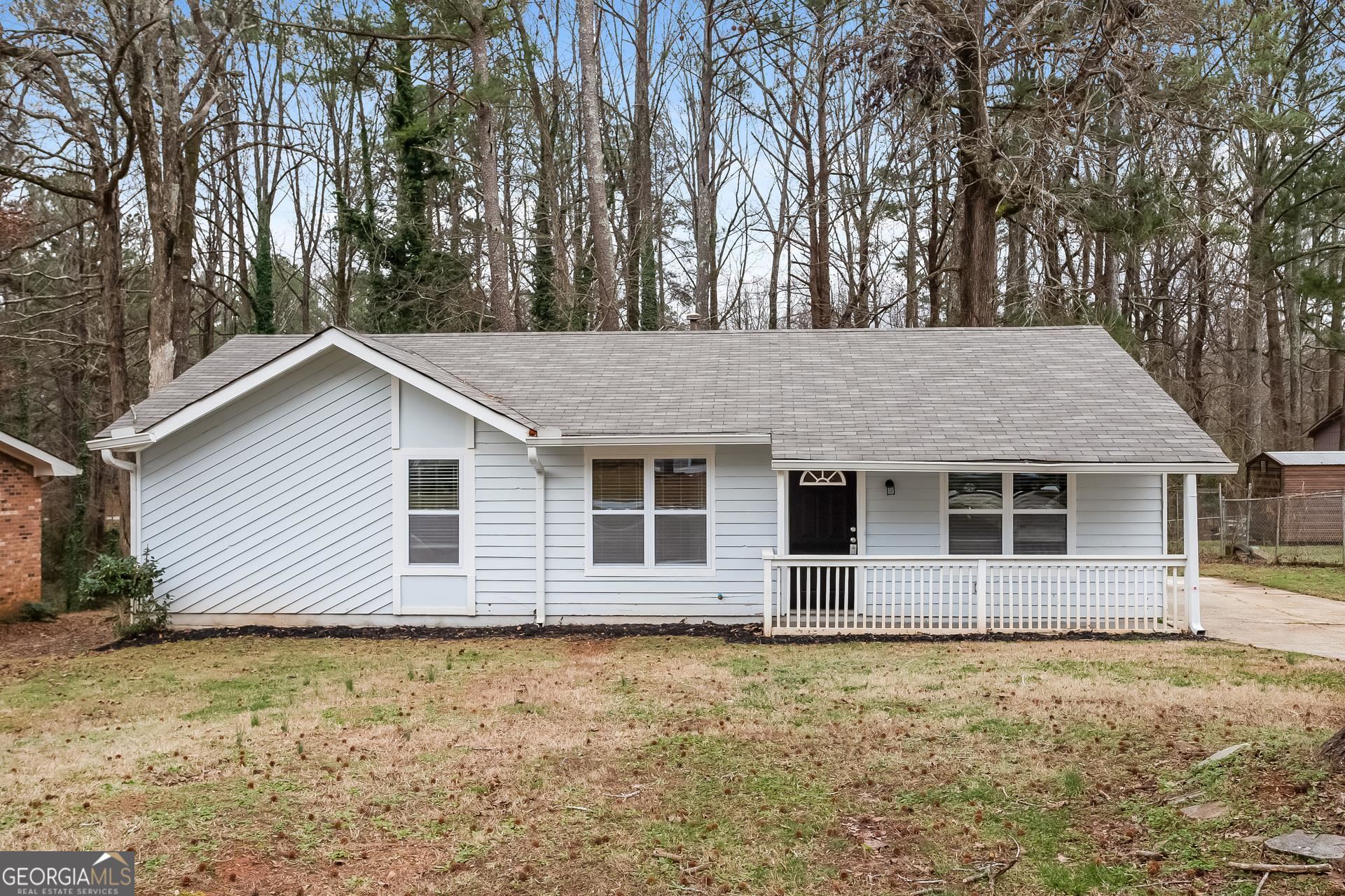 a backyard of a house with large trees and barbeque oven