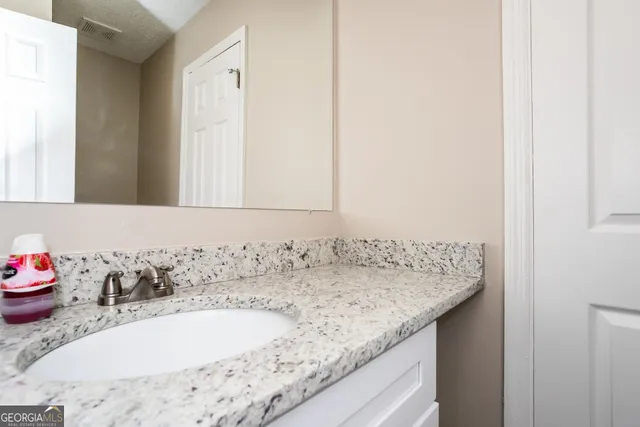 a bathroom with a granite countertop sink and a mirror