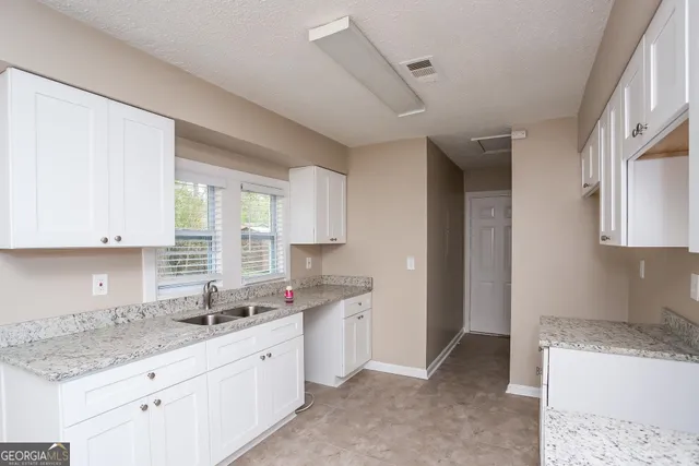 a kitchen with granite countertop a sink stove and cabinets
