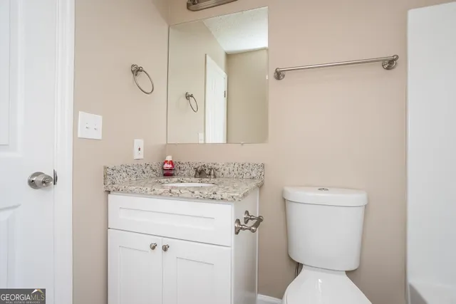 a bathroom with a toilet sink vanity and mirror