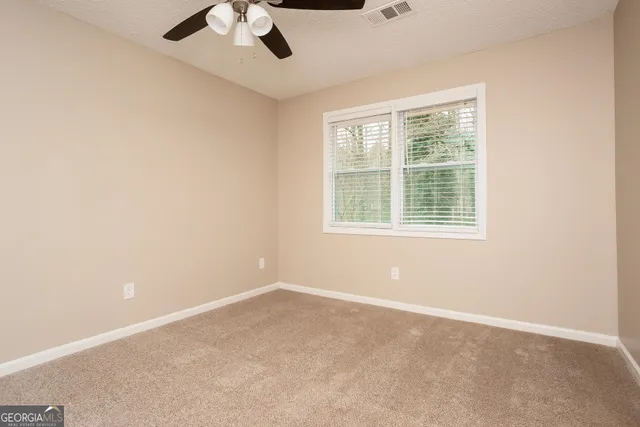 an empty room with a window and a ceiling fan