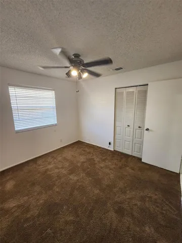 an empty room with a chandelier fan and windows