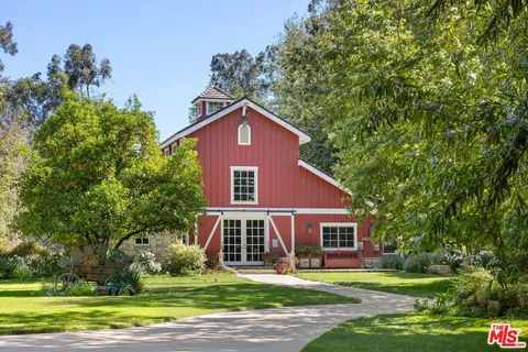 a view of a yard in front of a house with large windows