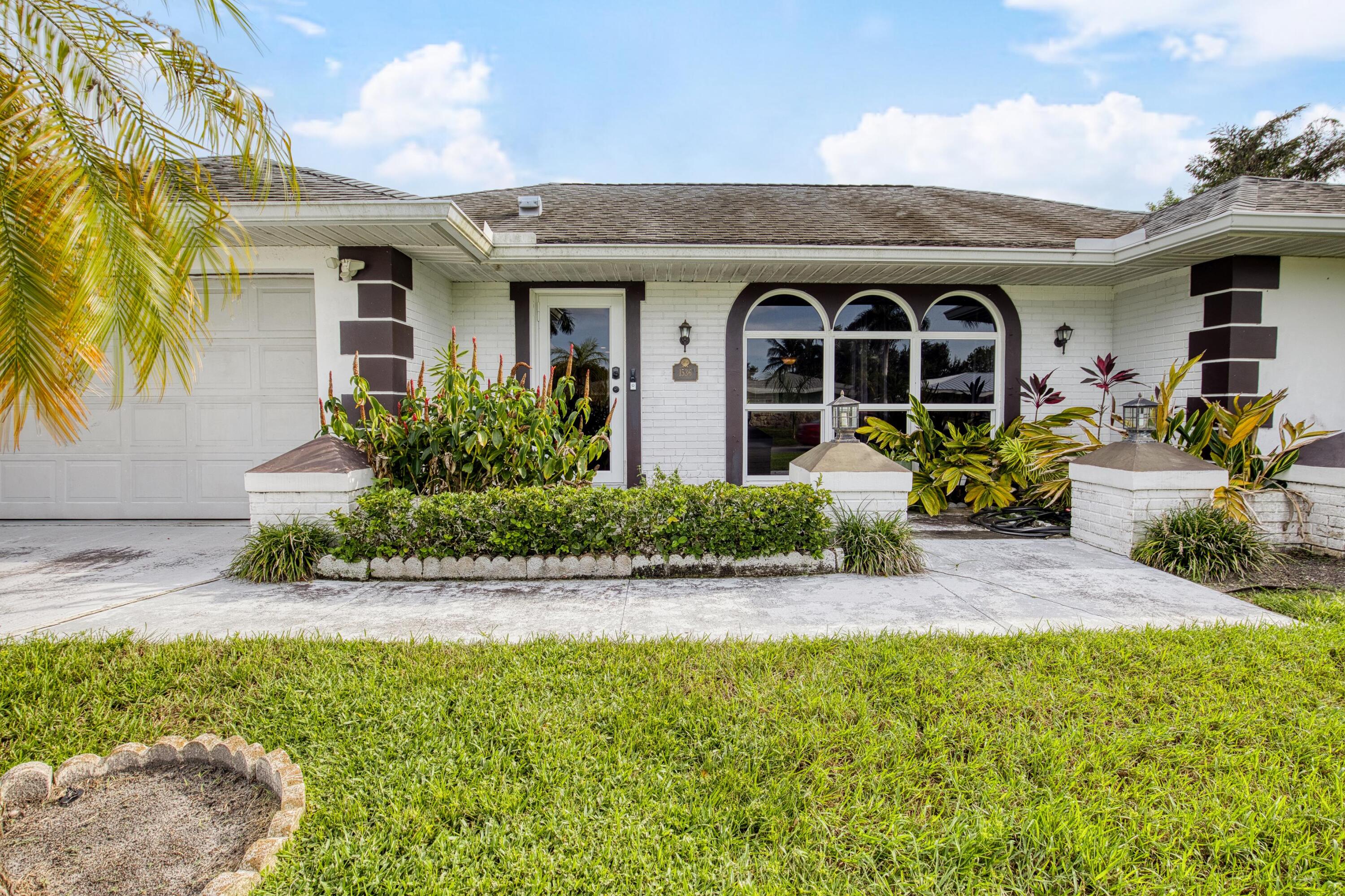 1536 Southeast Sunshine Avenue Port St. Lucie, FL 34952 - Photo 1 of 18 a front view of a house with garden