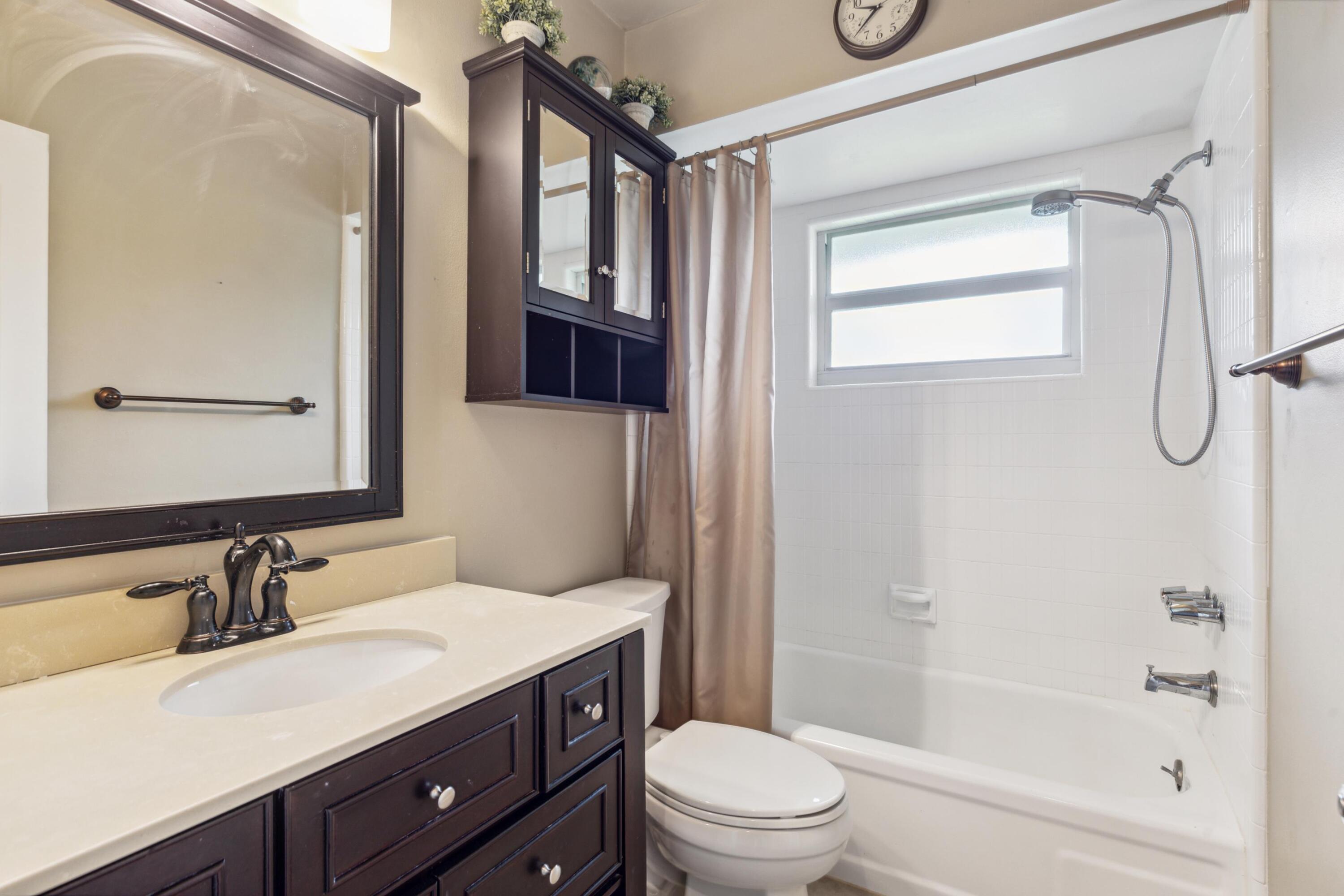 1536 Southeast Sunshine Avenue Port St. Lucie, FL 34952 - Photo 13 of 18 a bathroom with a granite countertop sink toilet a mirror a vanity and shower