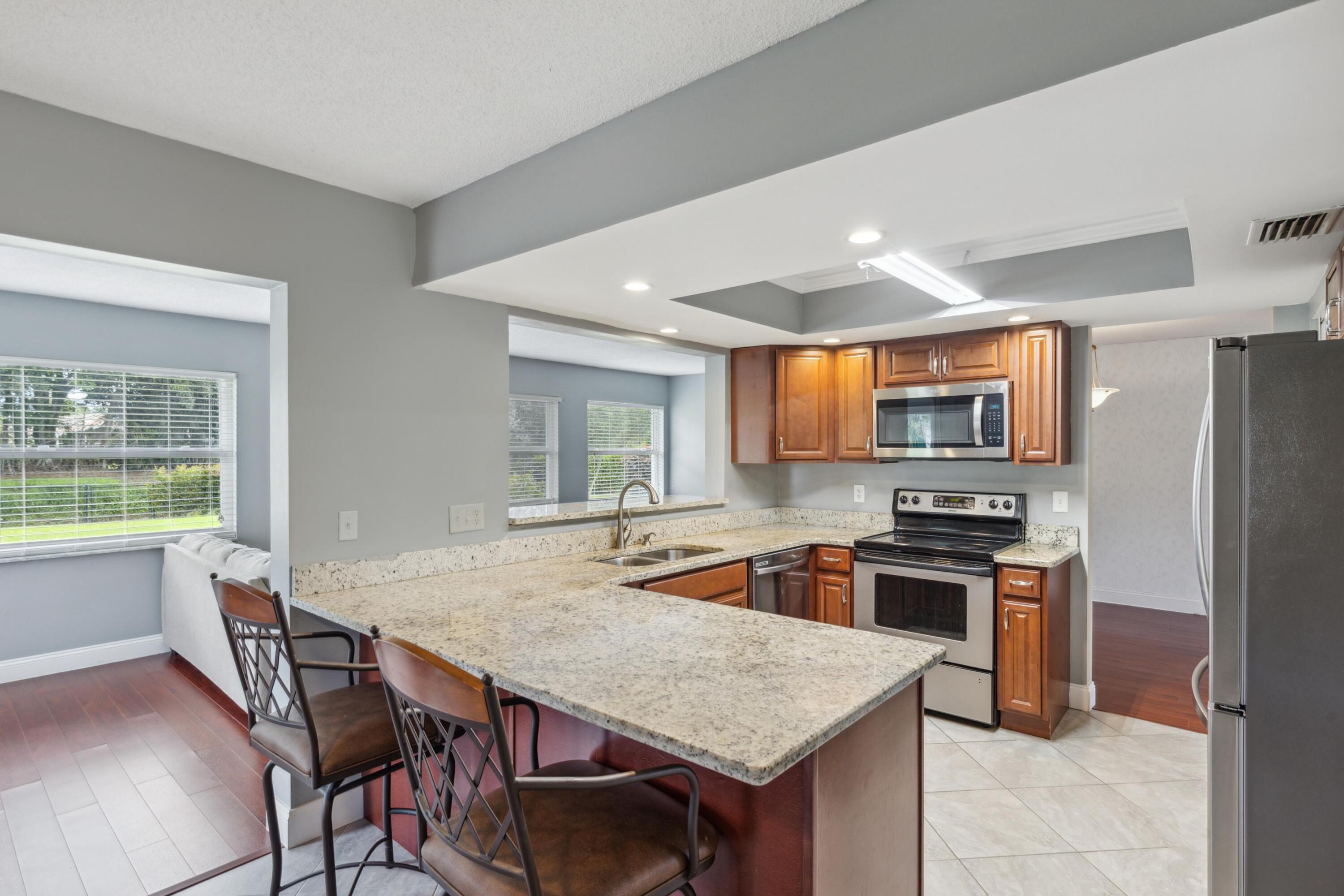 1536 Southeast Sunshine Avenue Port St. Lucie, FL 34952 - Photo 2 of 18 a kitchen with stainless steel appliances granite countertop a stove a refrigerator a sink a dining table and chairs