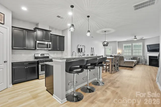 a kitchen with stainless steel appliances kitchen island granite countertop a refrigerator a stove a microwave oven a sink with island and chairs
