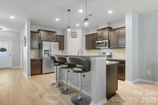 a kitchen with stainless steel appliances a dining table chairs and granite counter tops