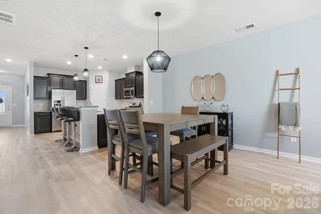 a kitchen with stainless steel appliances kitchen island granite countertop a dining table chairs and a wooden floor