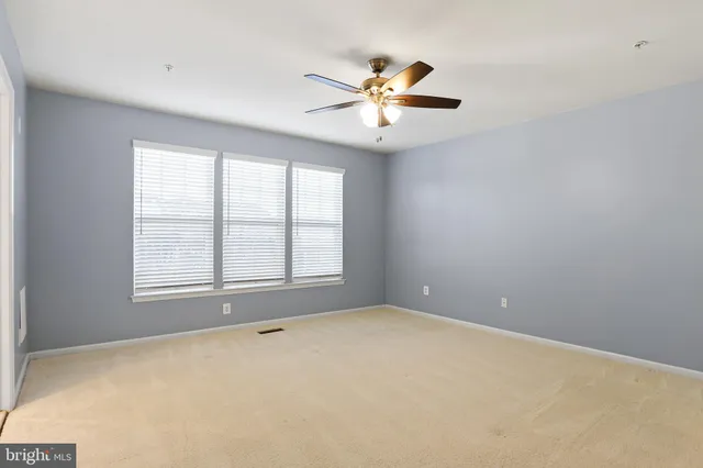 a view of an empty room with chandelier fan and a window