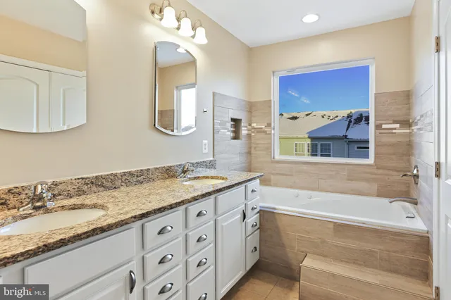 a bathroom with a granite countertop tub a double vanity sink and a mirror