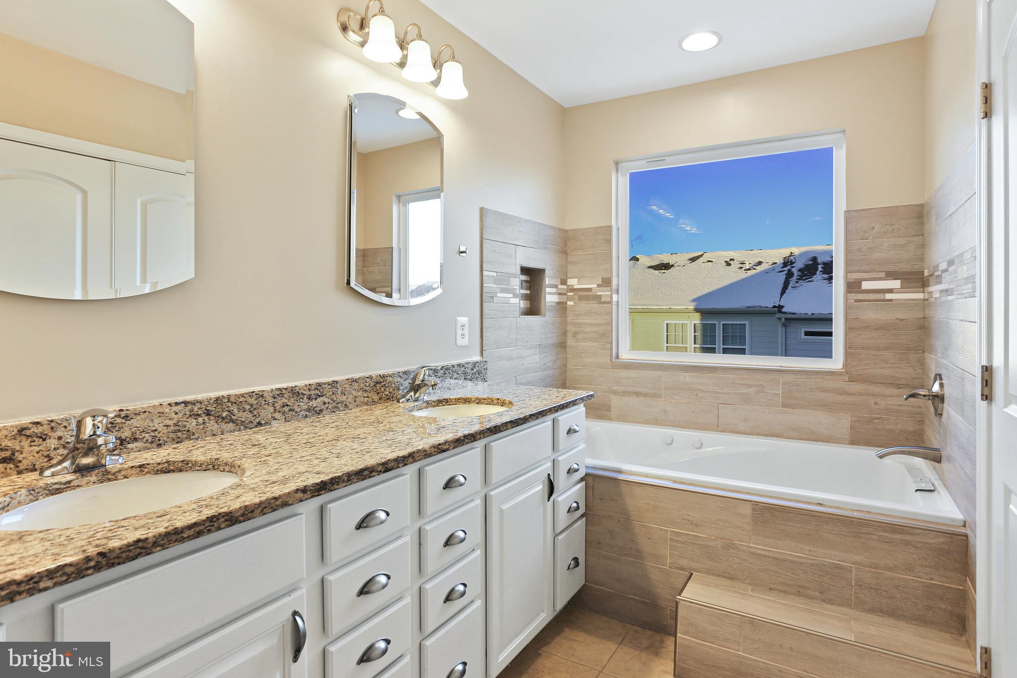 2719 Amber Crest Road Hanover, MD 21076 - Photo 9 of 22 a bathroom with a granite countertop tub a double vanity sink and a mirror