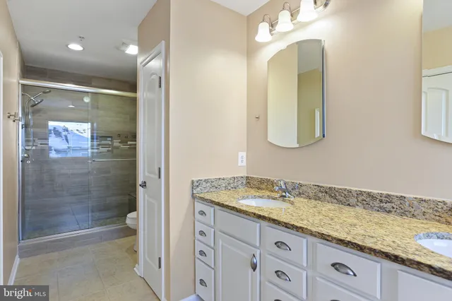 a bathroom with a granite countertop sink mirror and shower