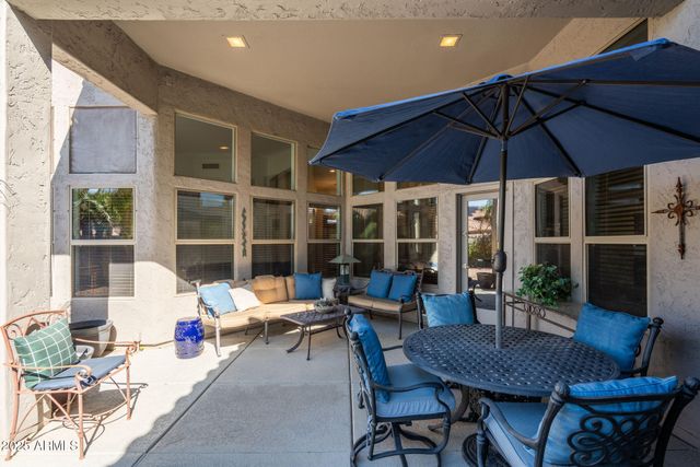 a view of a patio with a dining table and chairs under an umbrella