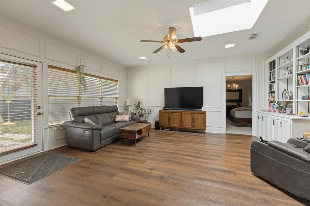 705 South Grove Road Richardson, TX 75081 - Photo 7 of 26 Spacious living area featuring wood-finish flooring, white paneling, and a built-in shelving unit with lower cabinetry