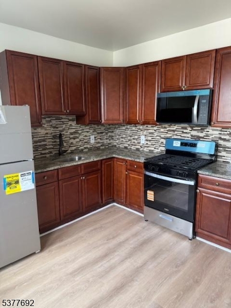 609 South 19th Street, Unit 2 Newark, NJ 07103 - Photo 2 of 8 a kitchen with stainless steel appliances granite countertop a stove a sink dishwasher and a microwave with wooden cabinets