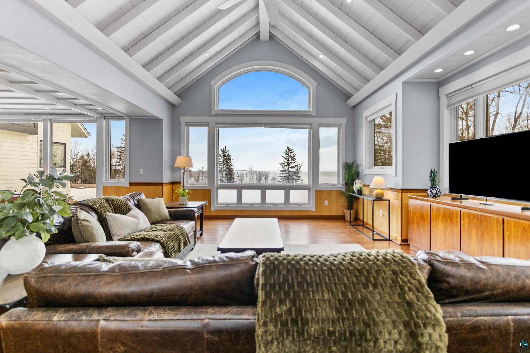 5163 Greenwood Road Duluth, MN 55804 - Photo 5 of 10 Vaulted ceiling with exposed white beams, complemented by a large arched window and additional picture windows