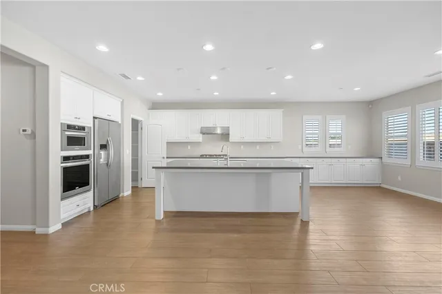 a large kitchen with stainless steel appliances a large counter top a stove and a refrigerator