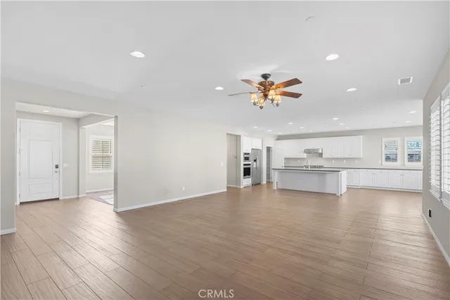 a view of empty room with wooden floor and kitchen view