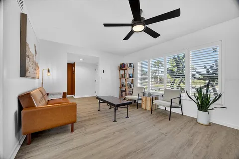 a living room with furniture ceiling fan and a large window