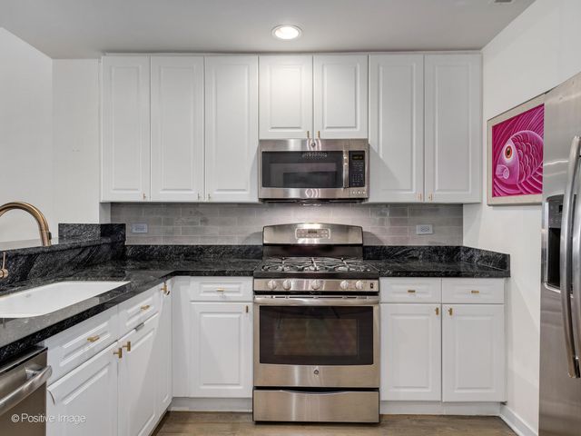 a kitchen with granite countertop white cabinets and stainless steel appliances