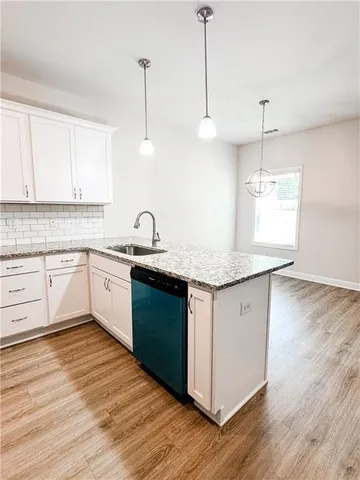 a kitchen with kitchen island granite countertop a sink cabinets and wooden floor