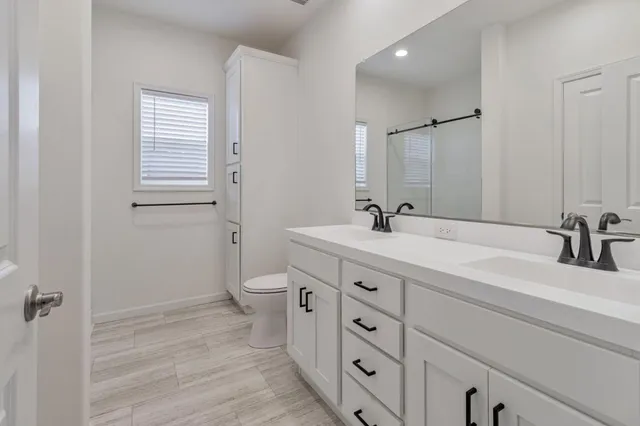 a bathroom with a double vanity sink toilet and shower