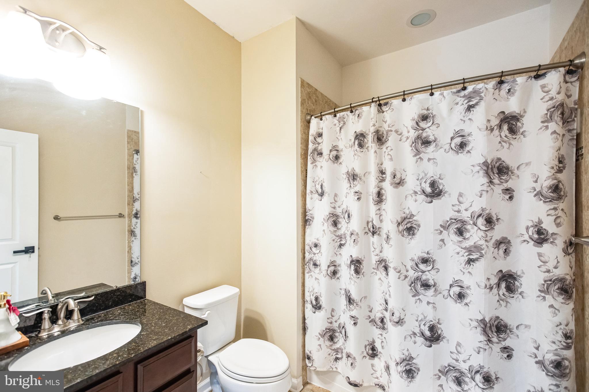 2601 St Marys View Road Accokeek, MD 20607 - Photo 24 of 33 a bathroom with a granite countertop toilet a sink a mirror and a shower curtain