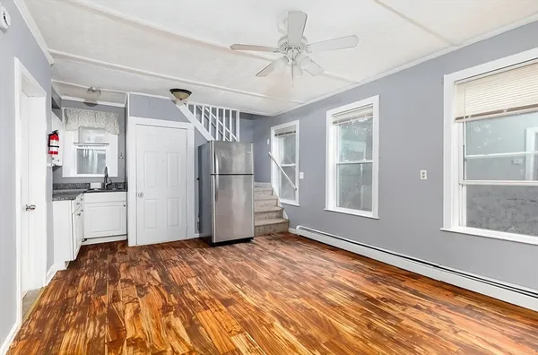 a view of empty room with wooden floor and fan