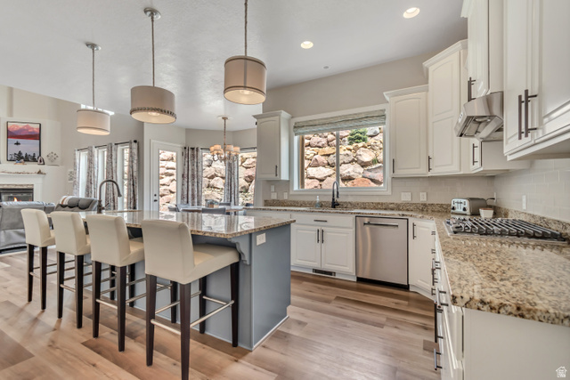 2543 East 700 South Springville, UT 84663 - Photo 73 of 73 Two tone kitchen featuring a kitchen bar, a center island with sink, light stone counters, open floor plan, and light wood-style flooring
