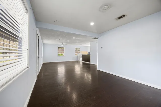 an empty room with wooden floor and windows