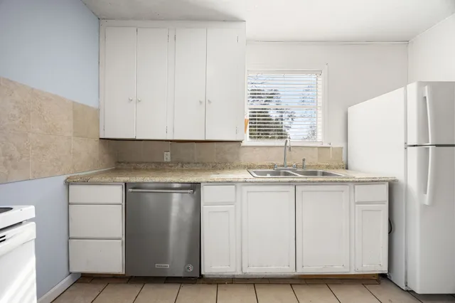 a kitchen with granite countertop white cabinets and white appliances