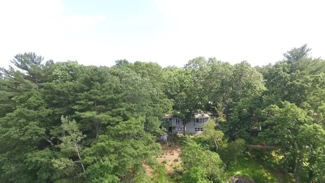 an aerial view of residential house with outdoor space and trees all around