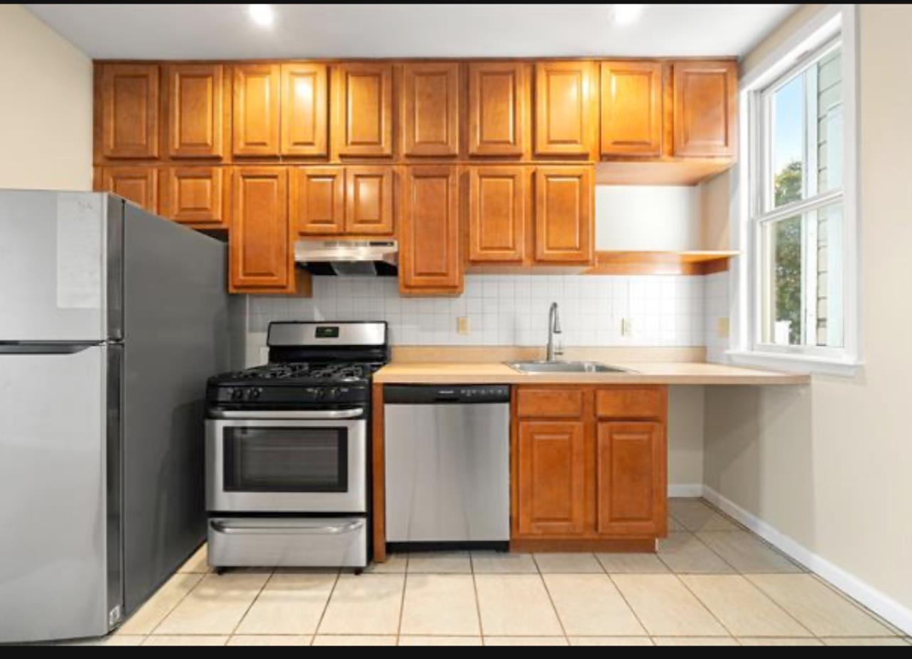 54 Monitor Street, Unit 4A Jersey City, NJ 07304 - Photo 3 of 10 a kitchen with stainless steel appliances granite countertop a stove a sink and a refrigerator with wooden cabinets