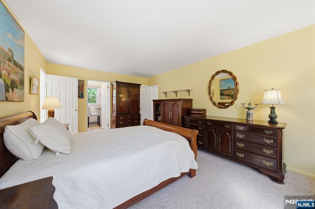 168 Engle Street Tenafly, NJ 07670 - Photo 27 of 50 a bedroom with a bed a mirror on dresser and a chandelier