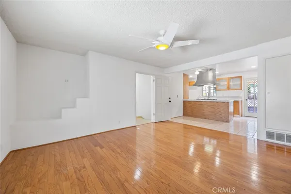 a view of an empty room with kitchen and window